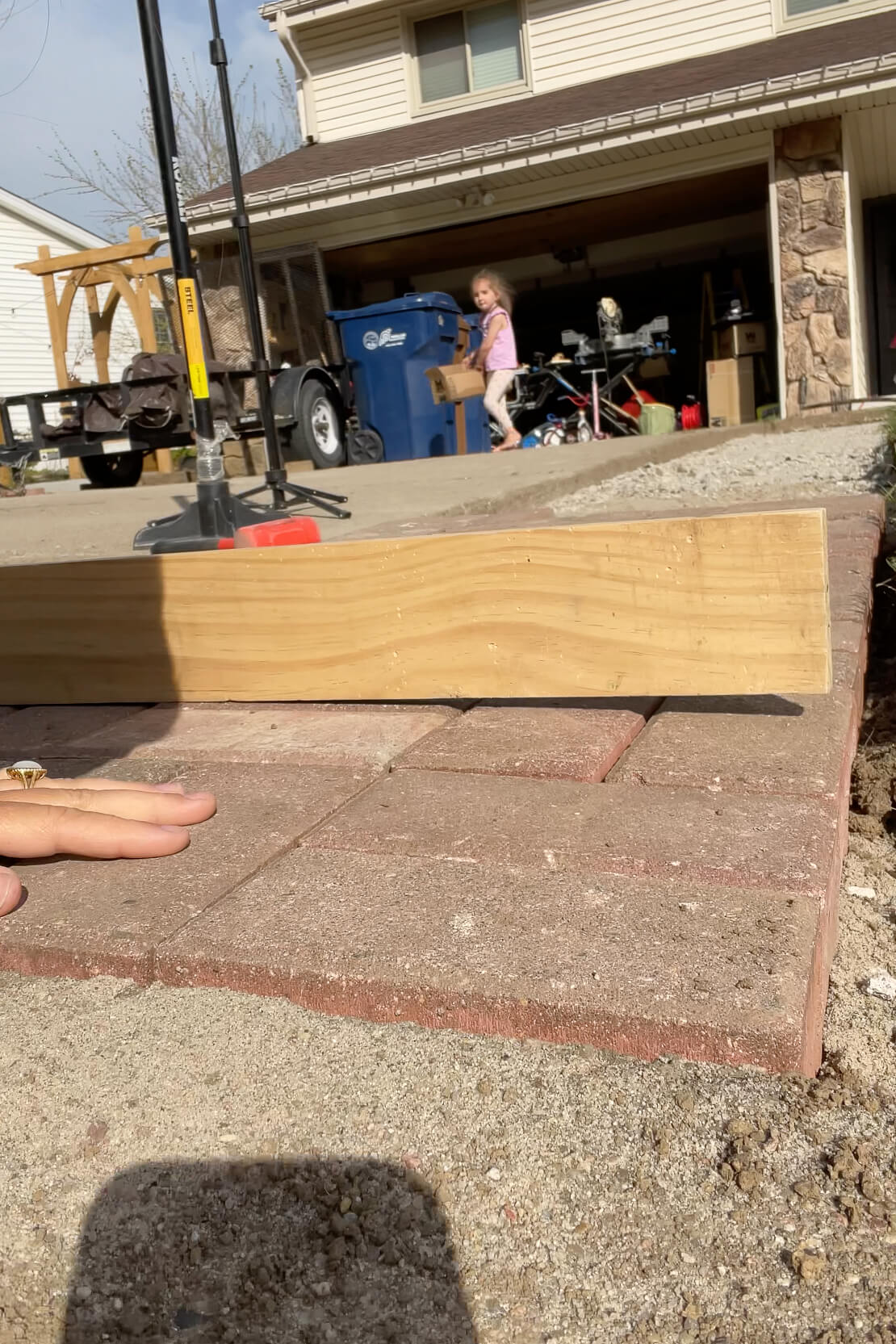 Using a board to make sure that pavers are being laid straight.